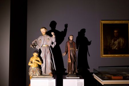 Das Bild zeigt Ausstellungsstücke aus dem Kreismuseum von Scheinwerfern angestrahlt, so dass sich deutlich der Schattenwurf hinter den Figuren zeigt.